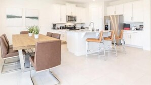A modern kitchen with white cabinets, a central island, and stainless steel appliances. - Amazing 4/3 Home at Reunion!! With Private Pool, Near Disney and Universal!! (Kissimmee)
