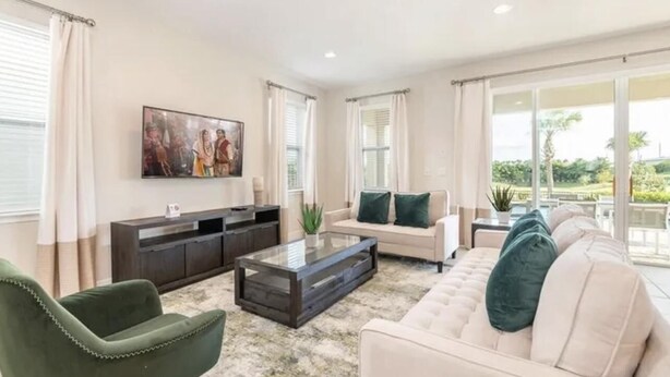 A spacious living room with a sofa set, a coffee table, and a TV. - Amazing 4/3 Home at Reunion!! With Private Pool, Near Disney and Universal!! (Kissimmee)
