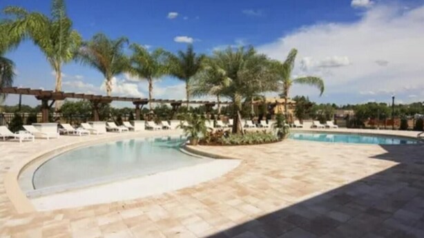 A pool area with lounge chairs and palm trees. - 4/3 Townhouse Near Disney!! (Kissimmee)