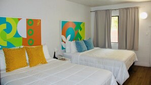 A hotel room with two beds, colorful abstract wall art, a telephone, and a window with curtains.