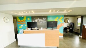 A reception desk with two monitors, a clock, and a colorful wall mural.