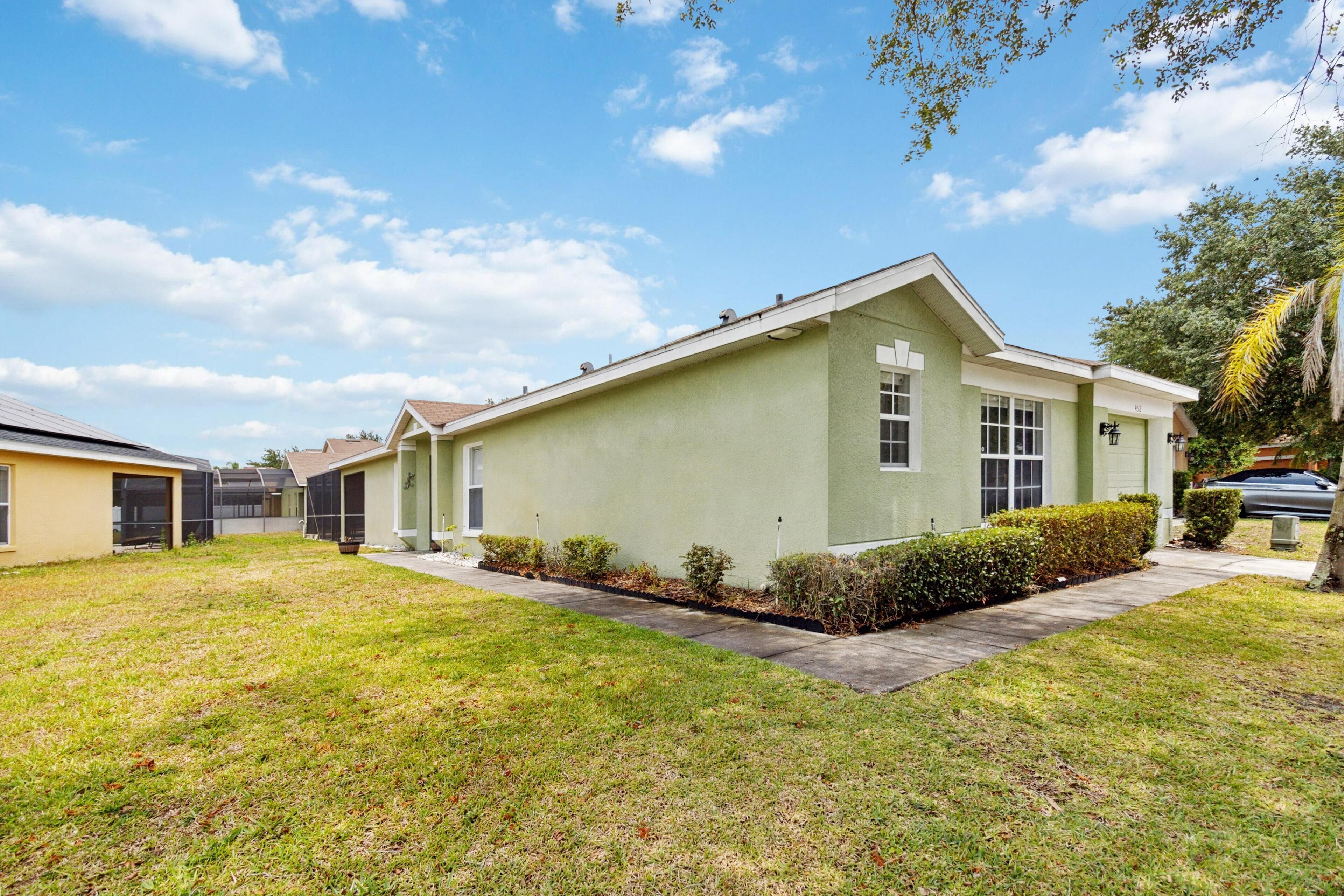 A single-story building with a flat roof, a front entrance, and a small front yard with a lawn and a hedge.