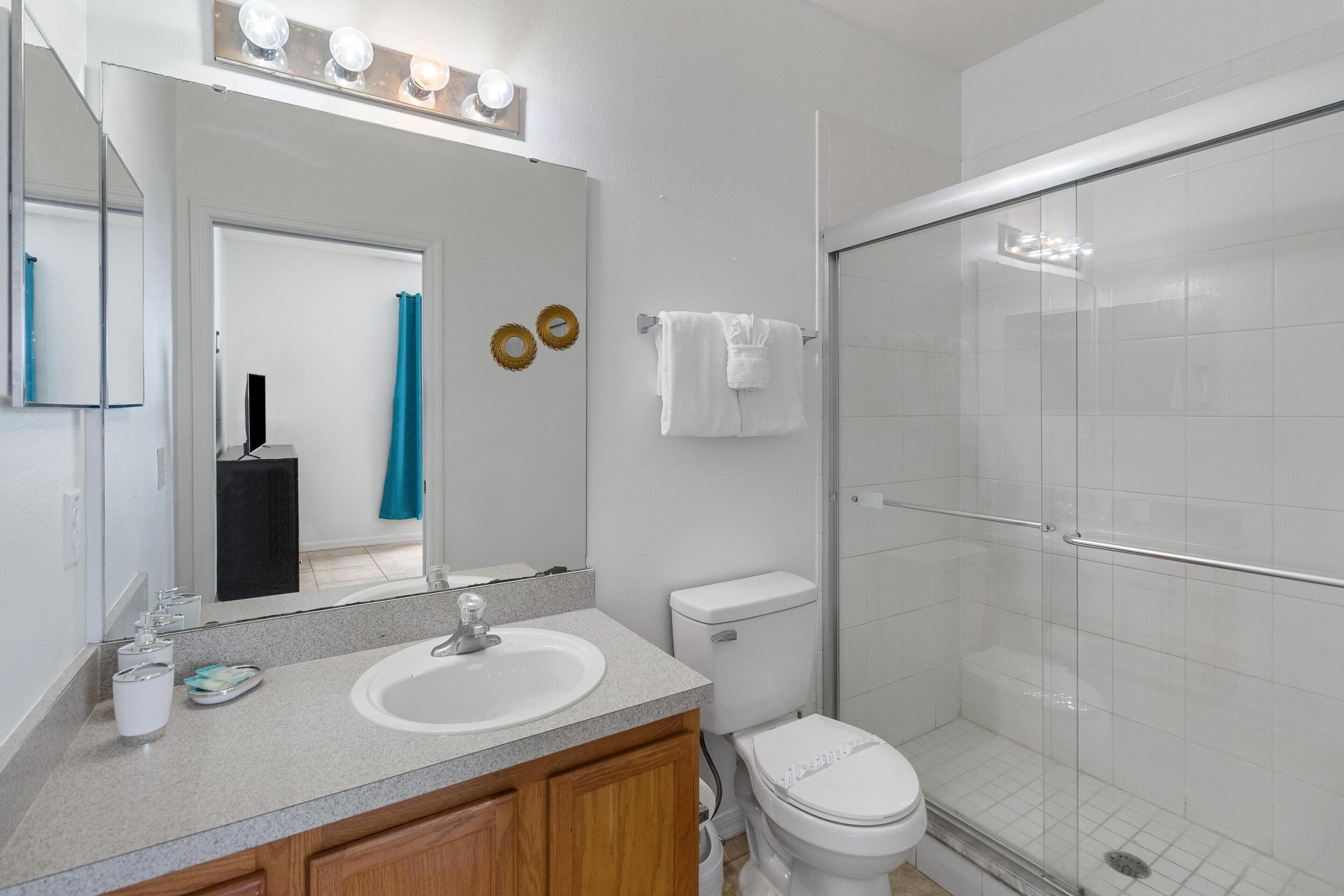A bathroom with a sink, toilet, and glass shower enclosure.