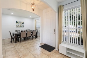 Uma área de refeições com mesa e cadeiras, uma porta branca e uma janela com vista para o exterior.