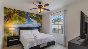 A bedroom with a bed, a ceiling fan, a nightstand, a TV, and a window with a view of the outside.
