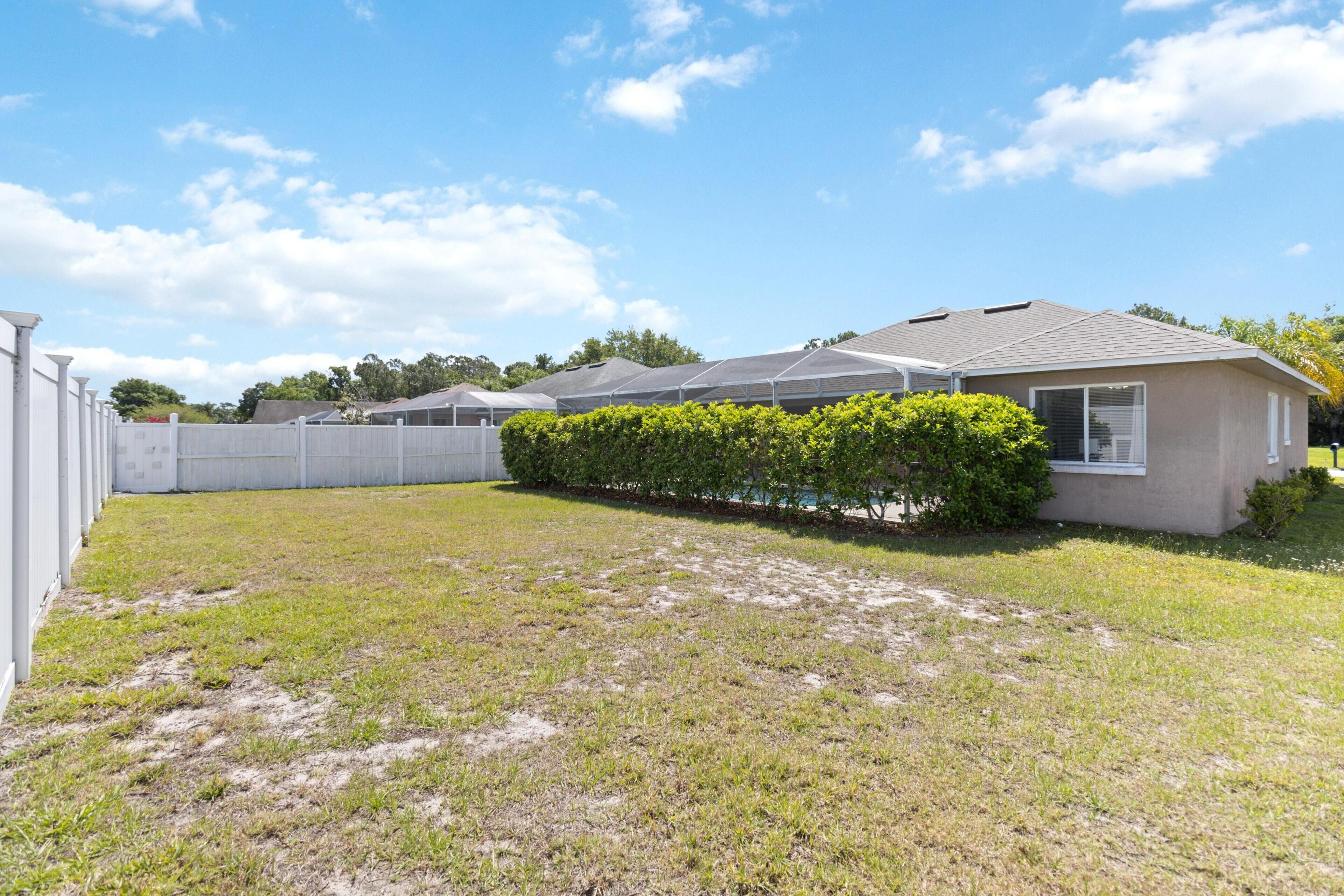 A row of single-story houses with a grassy yard and a white fence.