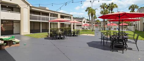 A hotel courtyard with outdoor seating, palm trees, and string lights.