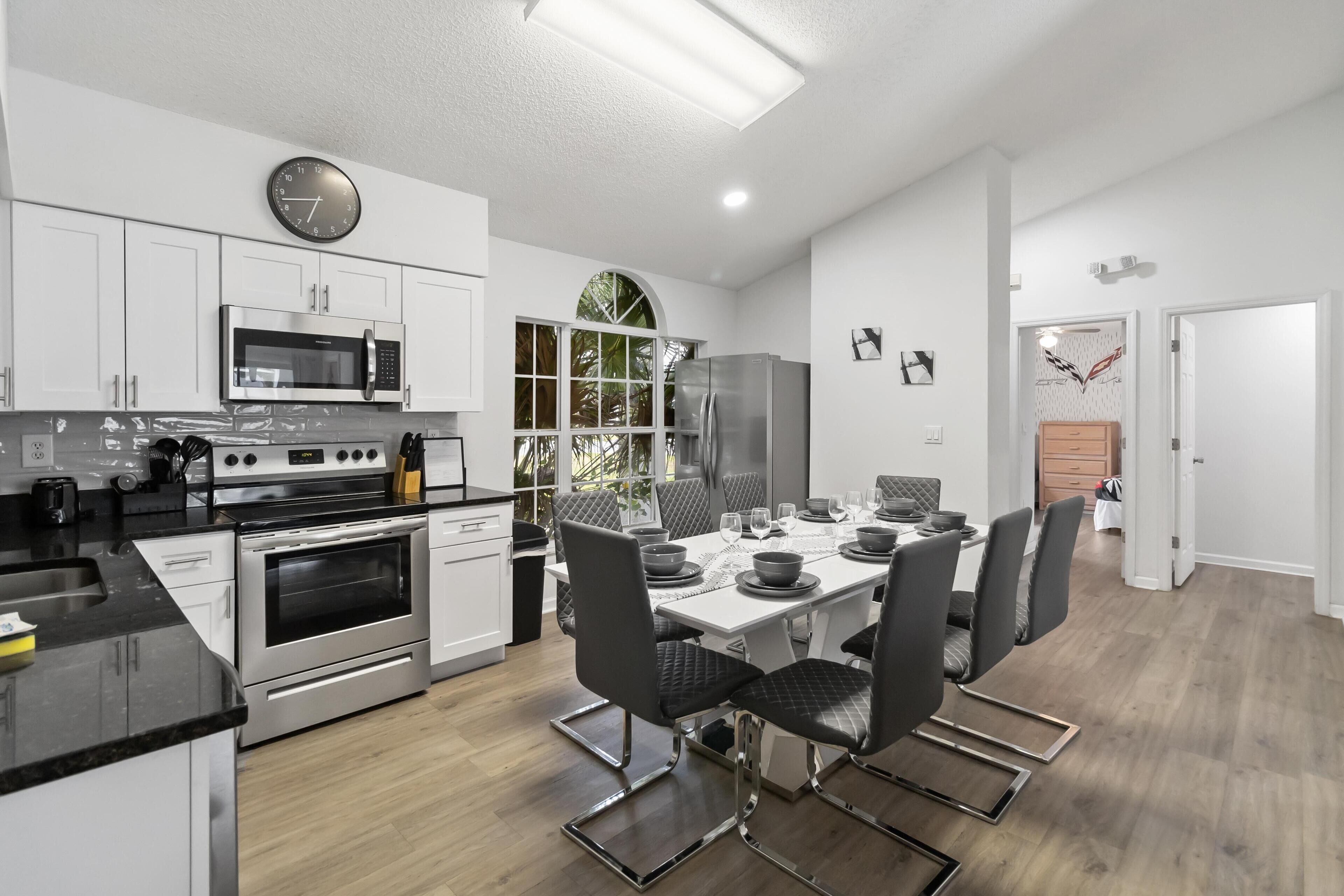 A modern kitchen with white cabinets, stainless steel appliances, and a dining area with a table set for four.