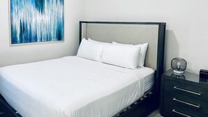 A neatly made bed with white linens, a modern headboard, and a small bedside table with a lamp. - Amazing 4/3 Home at Reunion!! With Private Pool, Near Disney and Universal!! (Kissimmee)