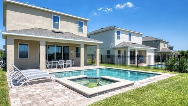 A residential property with a swimming pool, a patio with lounge chairs, and a well-maintained lawn. - Amazing 4/3 Home at Reunion!! With Private Pool, Near Disney and Universal!! (Kissimmee)
