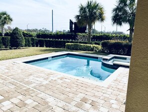 Una piscina rectangular amb una zona de maó, envoltada per uns testos ben cuidats i palmeres.