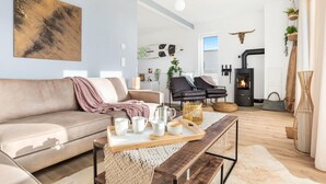 Una sala de estar moderna con un sofá, sillas, una mesa de centro y una chimenea.