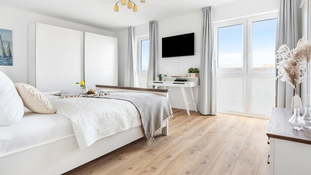Un dormitorio moderno con cama, escritorio y televisor.