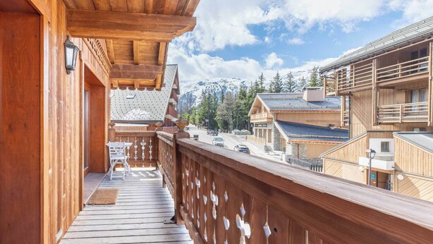 A wooden balcony with a view of a mountain and a town.