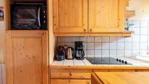 A kitchen with wooden cabinets, a microwave, a coffee maker, and an induction stove.