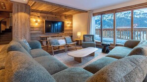 A cozy living room with a large sectional sofa, a small table, and a TV mounted on a wooden wall.