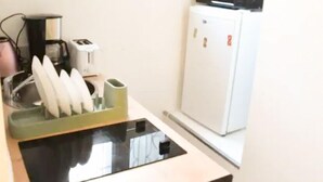 Una kitchenette compacta con microondas, refrigerador pequeño, tostadora y escurreplatos.