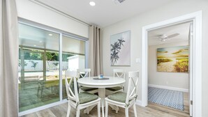 A dining area with a round table, four chairs, and a glass door leading to an outdoor space.