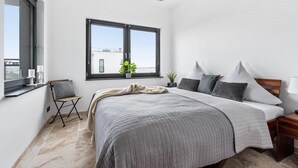 A modern bedroom with a large bed, a window with a view, a small table, and a bedside lamp. - Pet friendly apartment in Olpenitz (Olpenitz)