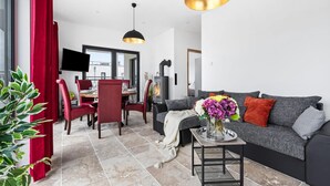A modern living room with a sofa, dining table, chairs, and a fireplace. - Pet friendly apartment in Olpenitz (Olpenitz)