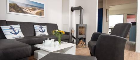 A modern living room with a sofa set, a coffee table with a vase of flowers, and a fireplace.