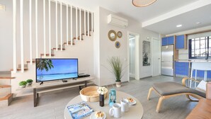 A modern living room with a TV, seating, a dining area, and a kitchen. - Meloneras Duplex (San Bartolomé de Tirajana)