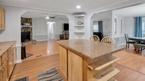 Une cuisine spacieuse dotée d’un îlot central avec un comptoir en granit, de meubles en bois et d’un coin repas comprenant une table et des chaises.