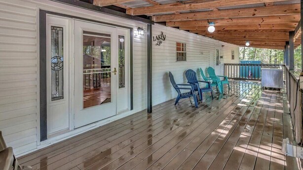Une véranda couverte avec des poutres en bois et un mur extérieur peint en blanc.