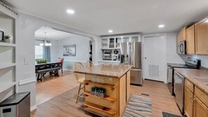 Une cuisine moderne dotée de meubles en bois, d’appareils électroménagers en acier inoxydable et d’un îlot central avec des sièges.