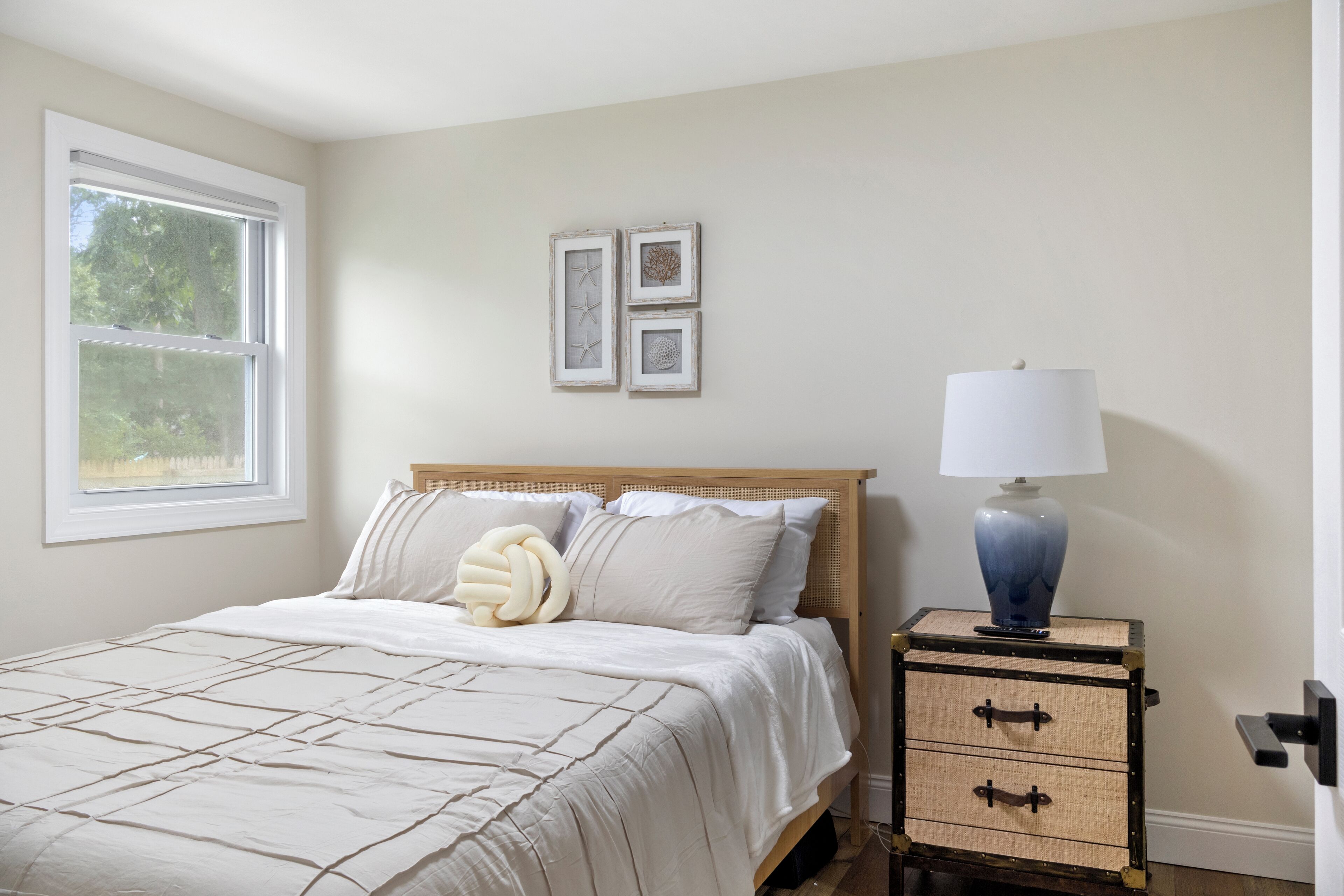 A bedroom with a bed, a nightstand with a lamp, and two framed pictures on the wall.