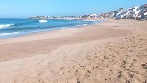 A beach with a clear sky, waves, and buildings along the shore. - Apartment Near the Beach (Bouznika)
