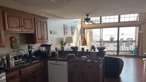 Una cocina con armarios de madera, lavavajillas y un ventanal con vistas a una terraza.