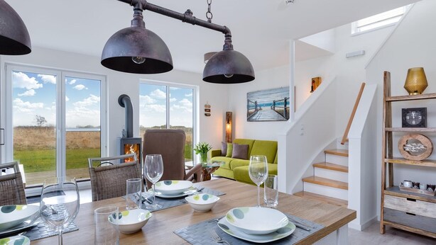A dining area with a wooden table set for four, a fireplace, and a staircase leading to an upper level. - Gorgeous home in Olpenitz with sauna (Olpenitz)