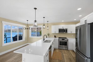 Una cocina moderna con gabinetes blancos, electrodomésticos de acero inoxidable y una isla grande.