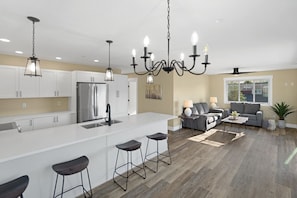 A modern kitchen with white cabinets, a stainless steel refrigerator, and a bar area with stools. - Marina Lookout - The best vibe in Veranda Beach (Oroville)