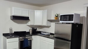 A modern kitchen with white cabinets, a stainless steel refrigerator, a microwave, and a stove. - Private apartment in Moncton (Moncton)