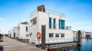 A waterfront building with a dock, featuring a modern design with large windows and a balcony. - Stunning ship in Olpenitz with sauna (Olpenitz)