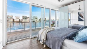 A modern bedroom with a large sliding glass door leading to a balcony overlooking a waterfront. - Stunning ship in Olpenitz with sauna (Olpenitz)