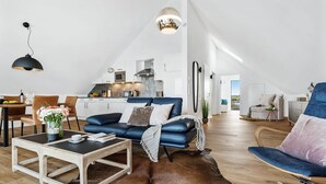 Un salón amplio con un sofá azul, una mesa de centro de madera y un comedor con sillas y una mesa.
