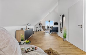 Camera da letto moderna tipo loft con soffitto spiovente, una grande finestra, un divano, una scrivania e un'area pranzo.