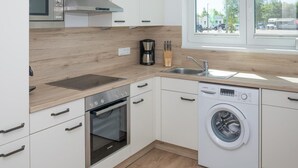 A modern kitchen with white cabinets, a Bosch microwave, a coffee maker, a sink, and a washing machine. - Beautiful home in Olpenitz with sauna (Olpenitz)