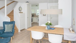 A modern kitchen with white cabinets, a wooden staircase, and a dining area with a wooden table and chairs. - Beautiful home in Olpenitz with sauna (Olpenitz)