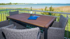 A wooden table with wicker chairs on a balcony overlooking a body of water. - Beautiful home in Olpenitz with sauna (Olpenitz)