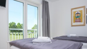 A hotel room with two beds, a large window with a view of a balcony, and a framed picture on the wall. - Beautiful home in Olpenitz with sauna (Olpenitz)