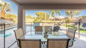 Een glazen patio met een zwembad, buitenzitplaatsen en uitzicht op een woonwijk.