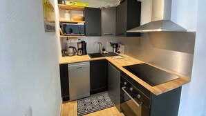 Una cucina compatta con forno a microonde, macchina del caffè, lavello e piano cottura.