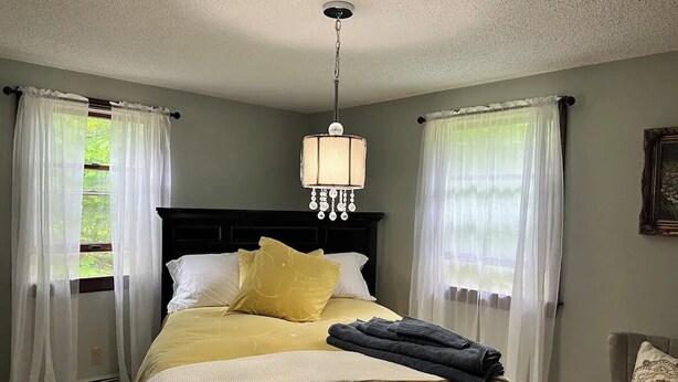 A bedroom with a bed, a chandelier, and curtains. - Wellness Gardens Retreat

 (Sidney)