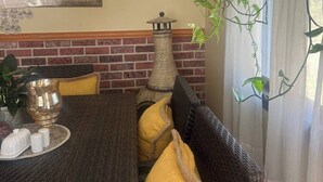 A dining area with a brick wall, a table with a candle holder, and a hanging plant. - Wellness Gardens Retreat

 (Sidney)