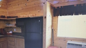 A compact kitchen with wooden walls, a sink, a microwave, and a refrigerator. - Charming 2-bedroom cabin in St Mary’s Glacier (Babb)
