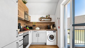 Une cuisine moderne dotée d’un lave-linge encastré, de meubles en bois et d’une grande fenêtre.